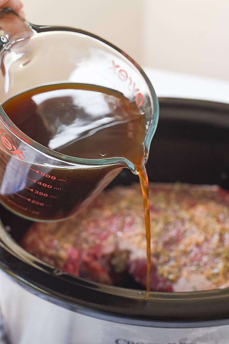 pouring broth over roast