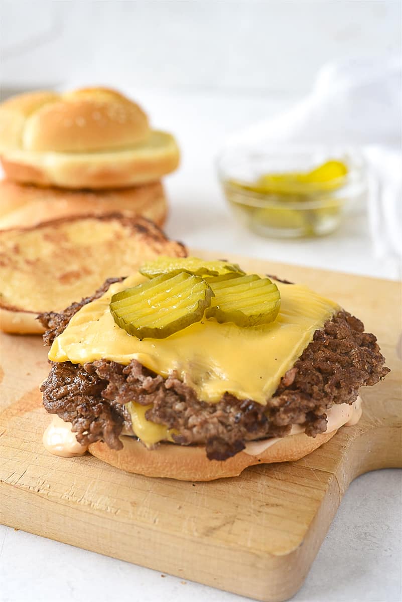 smash burger with pickles on top