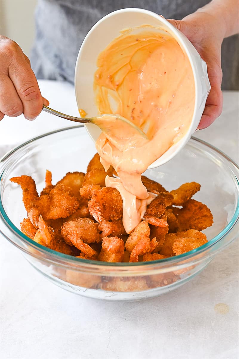 pouring sauce over firecracker shrimp