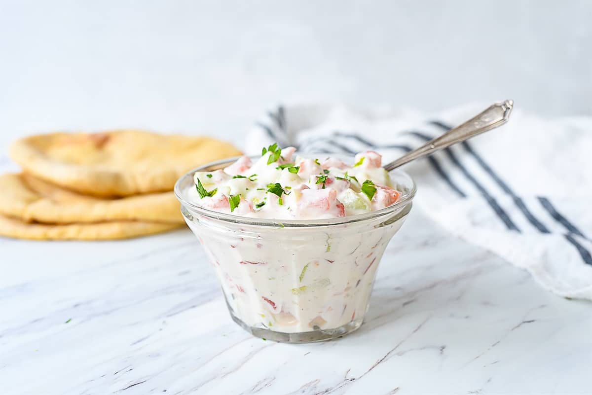 Tzatziki sauce in a bowl with parsley on top
