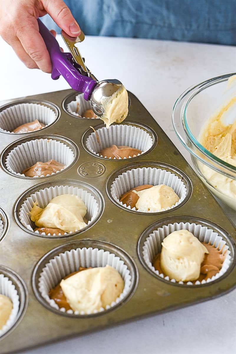 adding cupcake batter to muffin tin