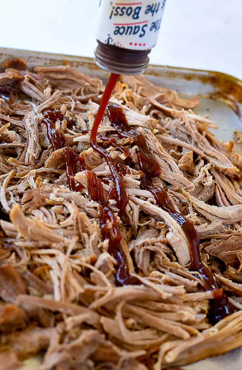 pouring bbq sauce on shredded pork