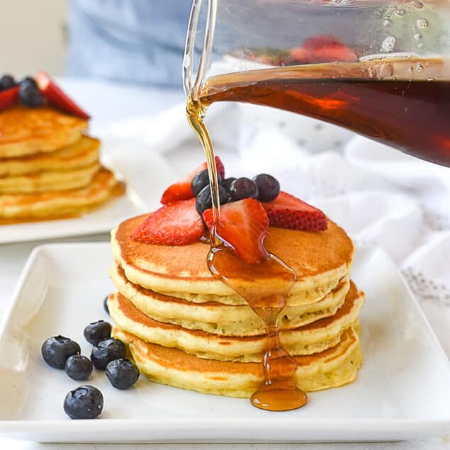 pouring syrup over pancakes