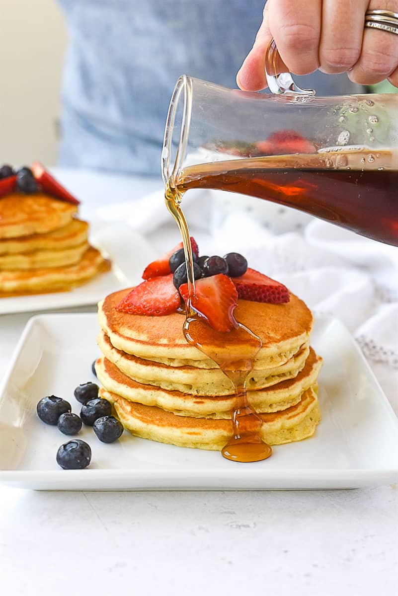 pouring syrup over pancakes