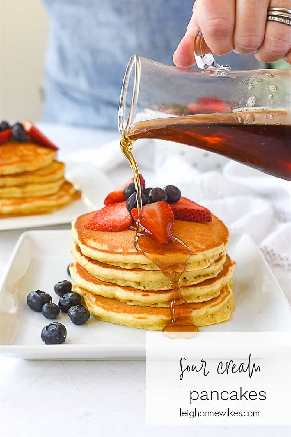 pouring syrup on a stack of pancakes