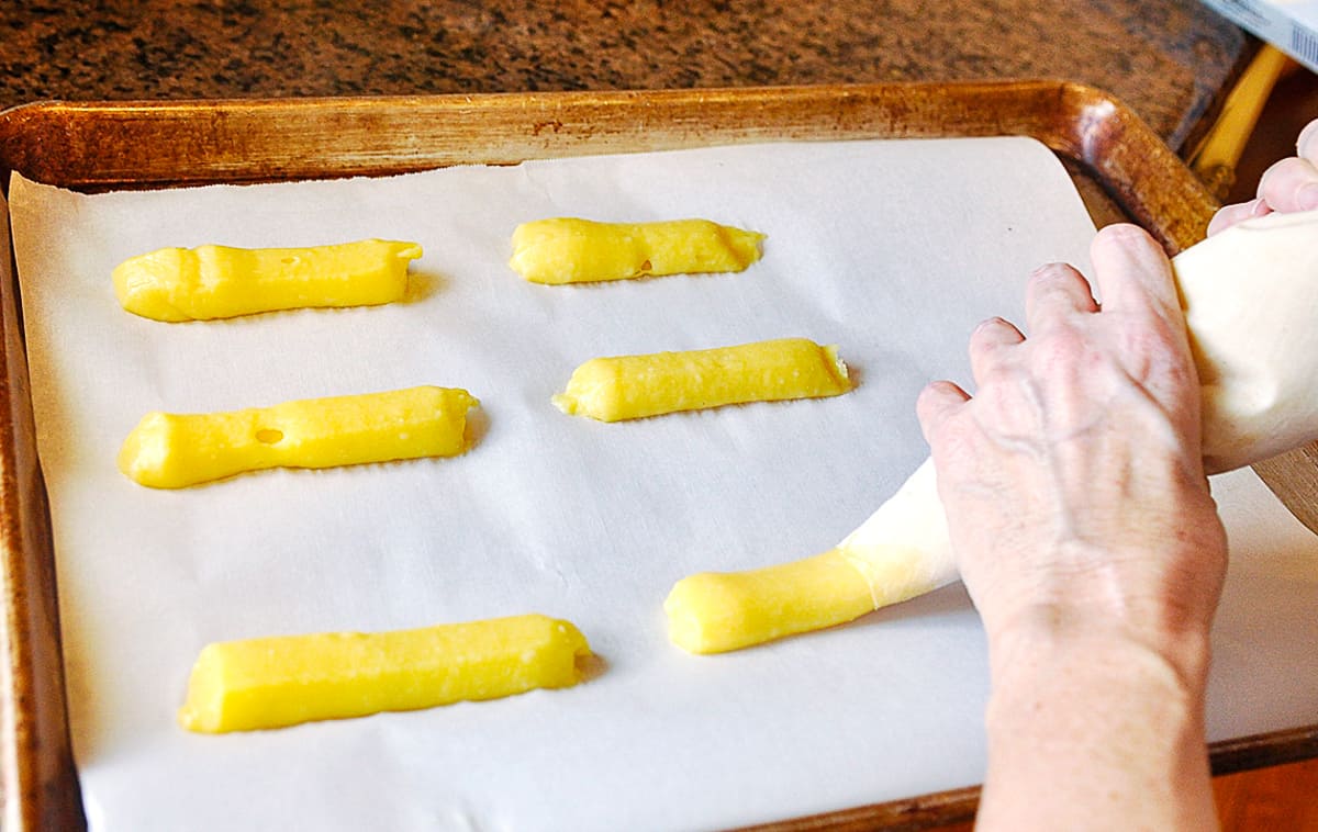 piping eclairs onto baking sheet