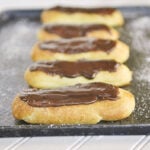 chocolate eclairs on a baking sheet