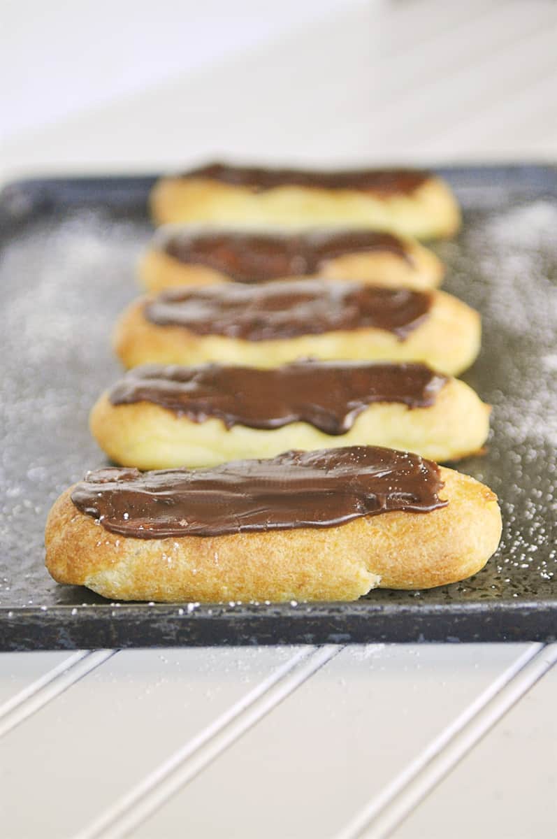 chocolate eclairs on a baking sheet