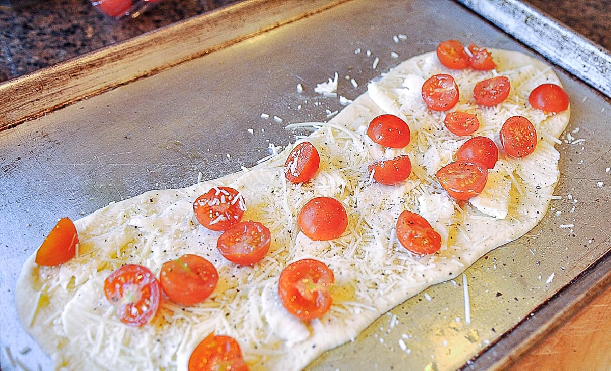 pizza dough with tomatoes on it