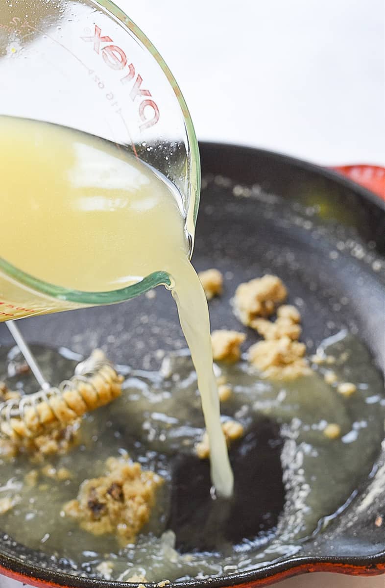 pouring chicken broth into pan.