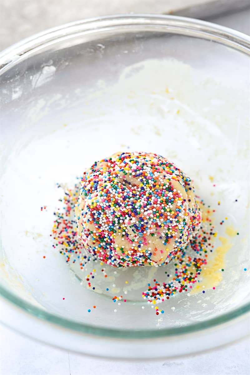 rolling cookie dough in sprinkles.