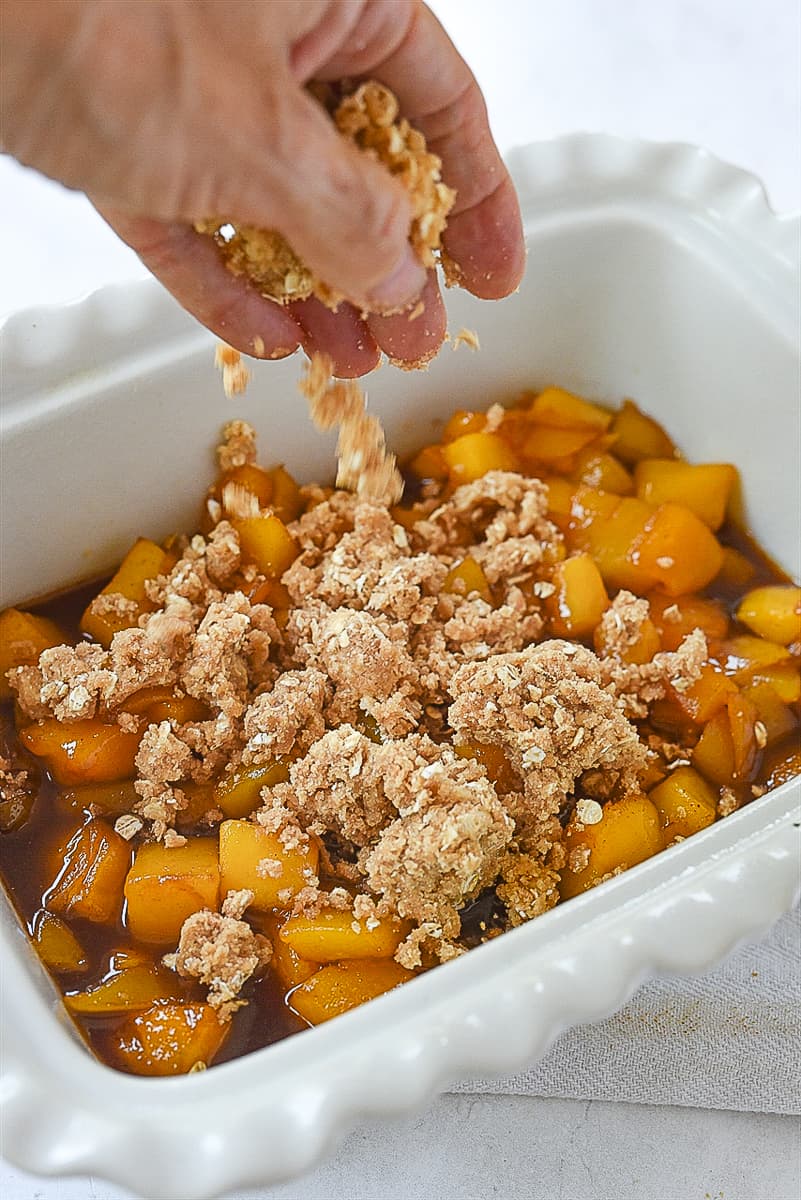 sprinkling crumble mixture over mangos