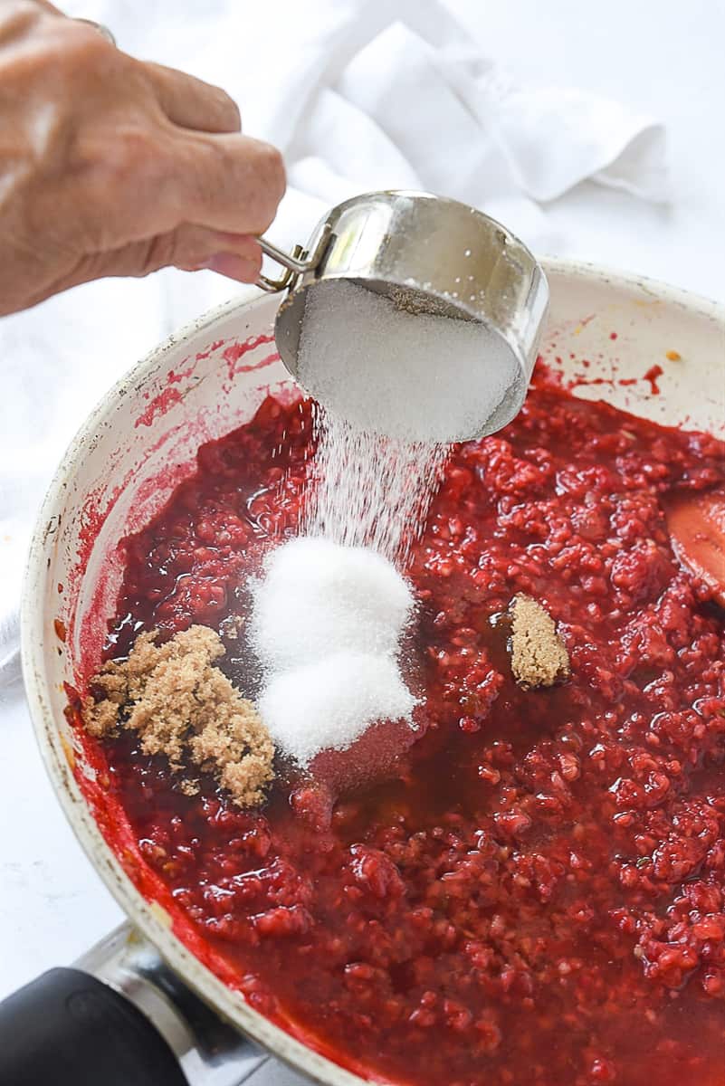 adding sugar into raspberry chipotle sauce