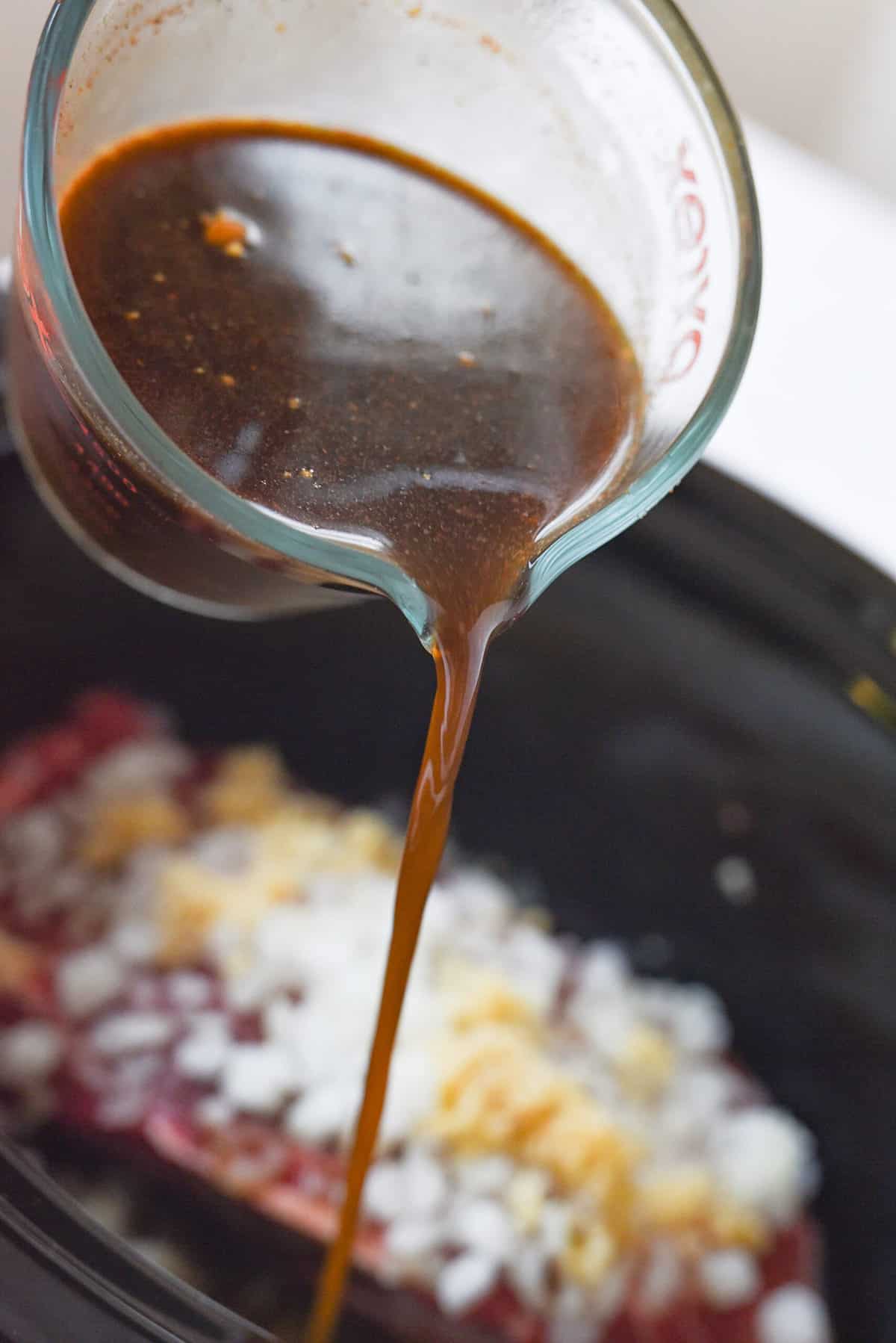 pouring sauce over meat in crock pot