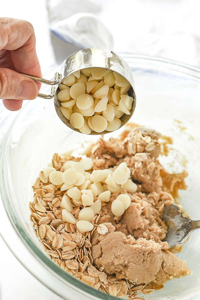 adding white chocolate chips into cookie dough