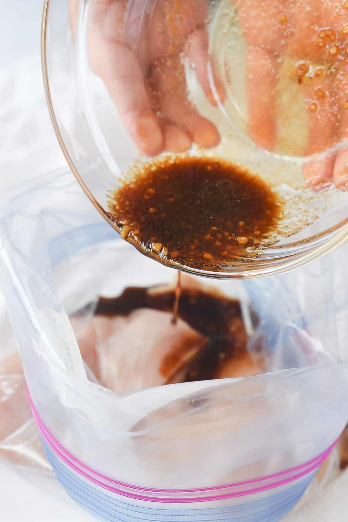 pouring chicken marinade into bag