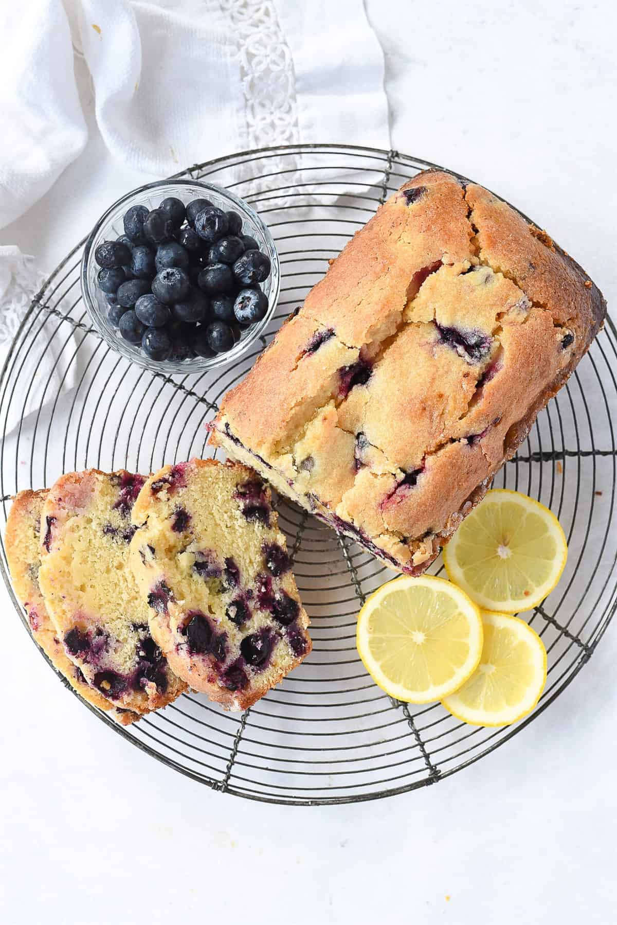 loaf of blueberry bread sliced on a cooling rack