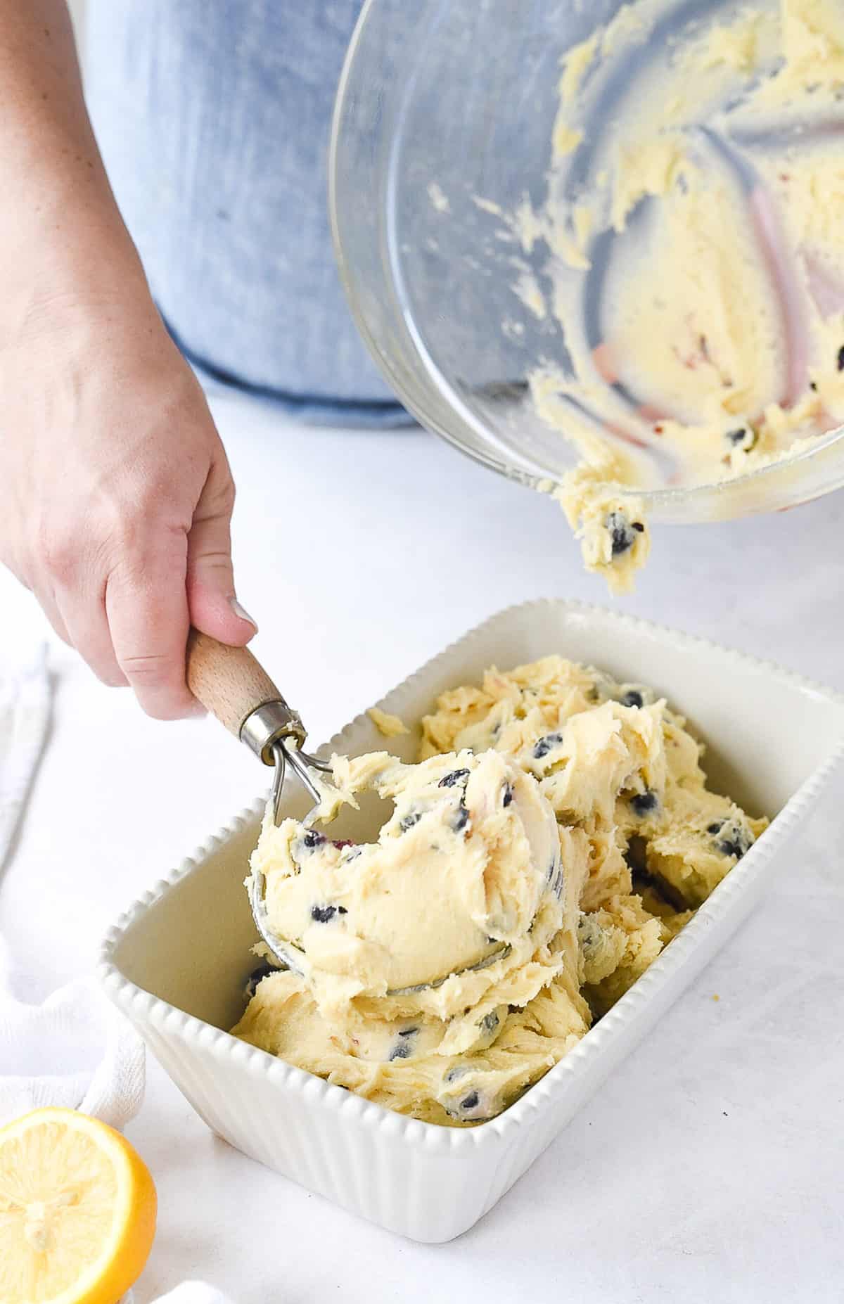 putting blueberry bread batter into a loaf pan