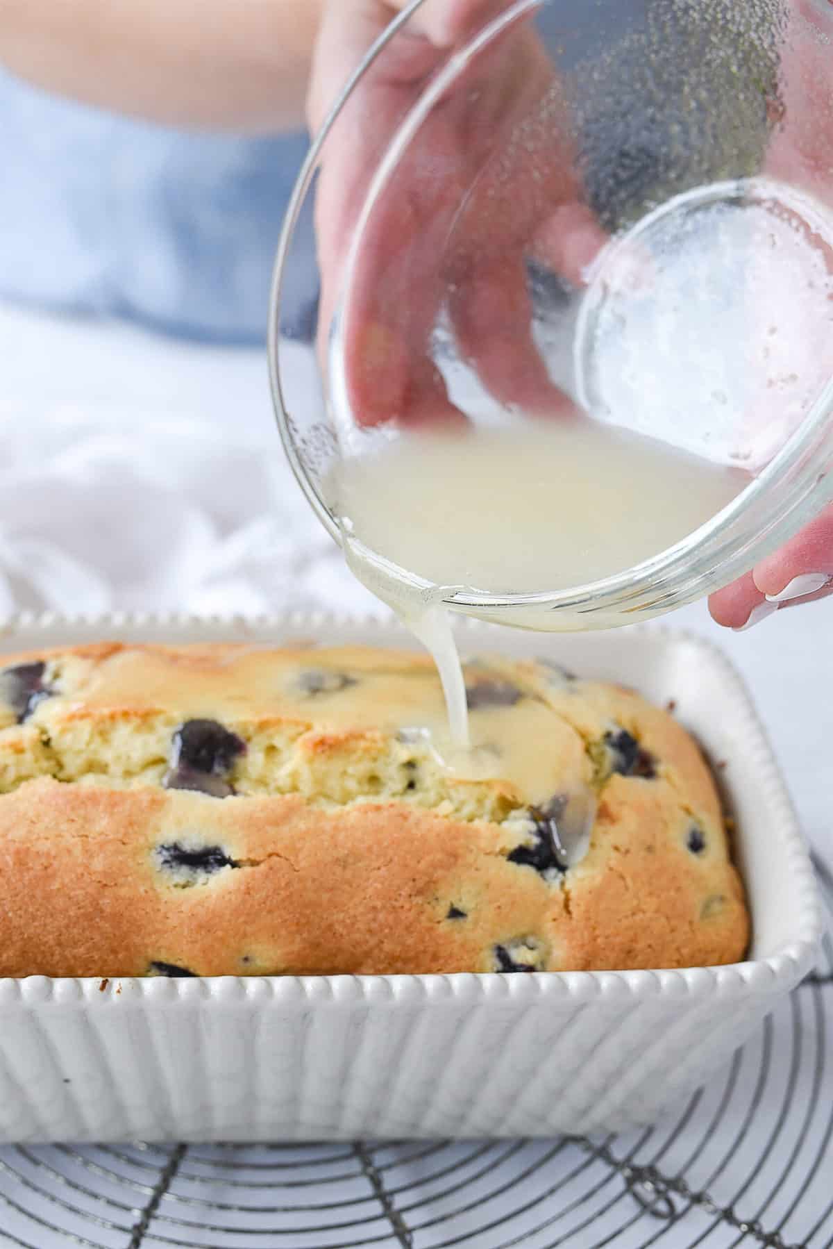 pouring glaze over blueberry bread