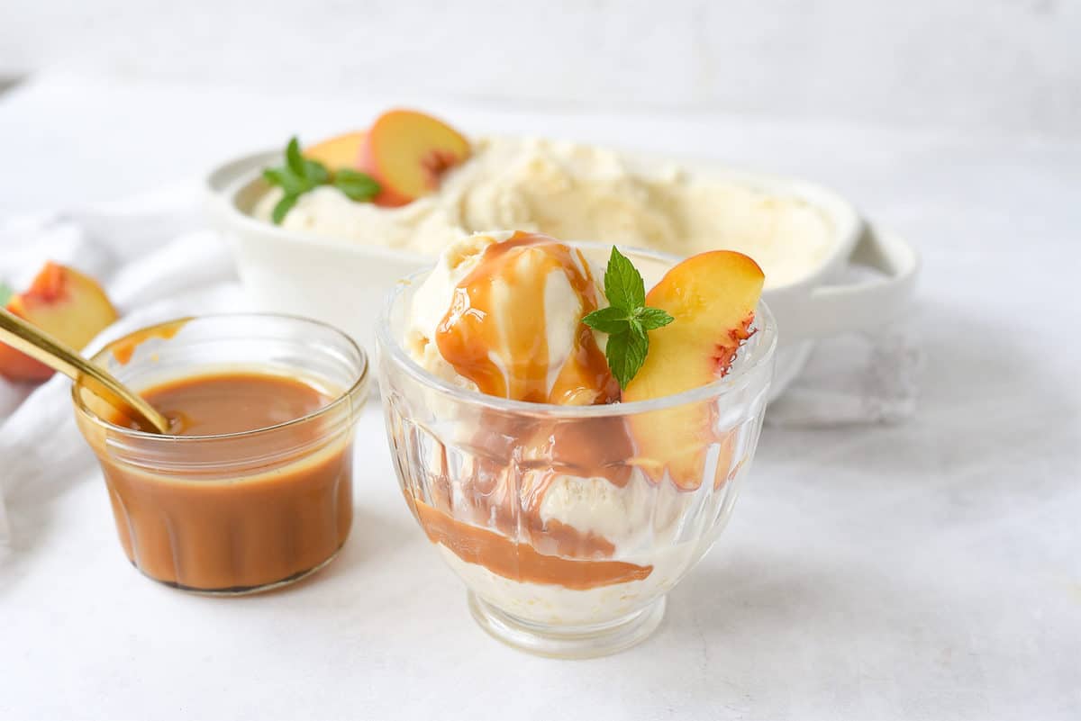 clear glass dish of peach ice cream with caramel sauce on it