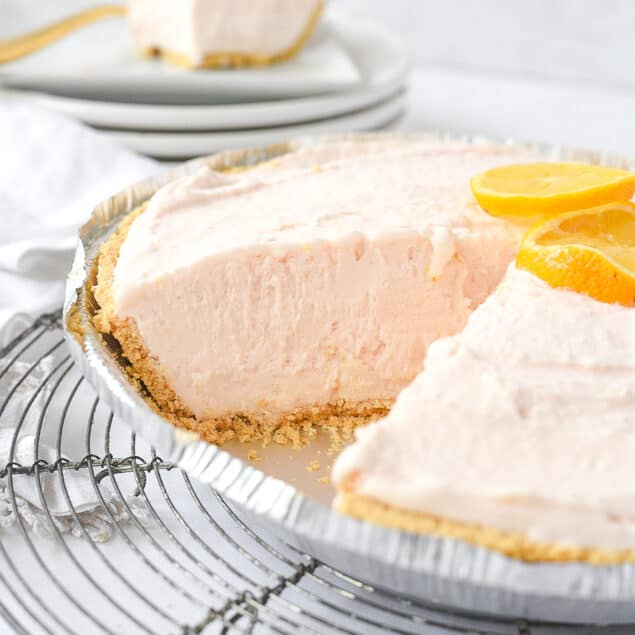 pink lemonade pie on a rack with a piece mkissing