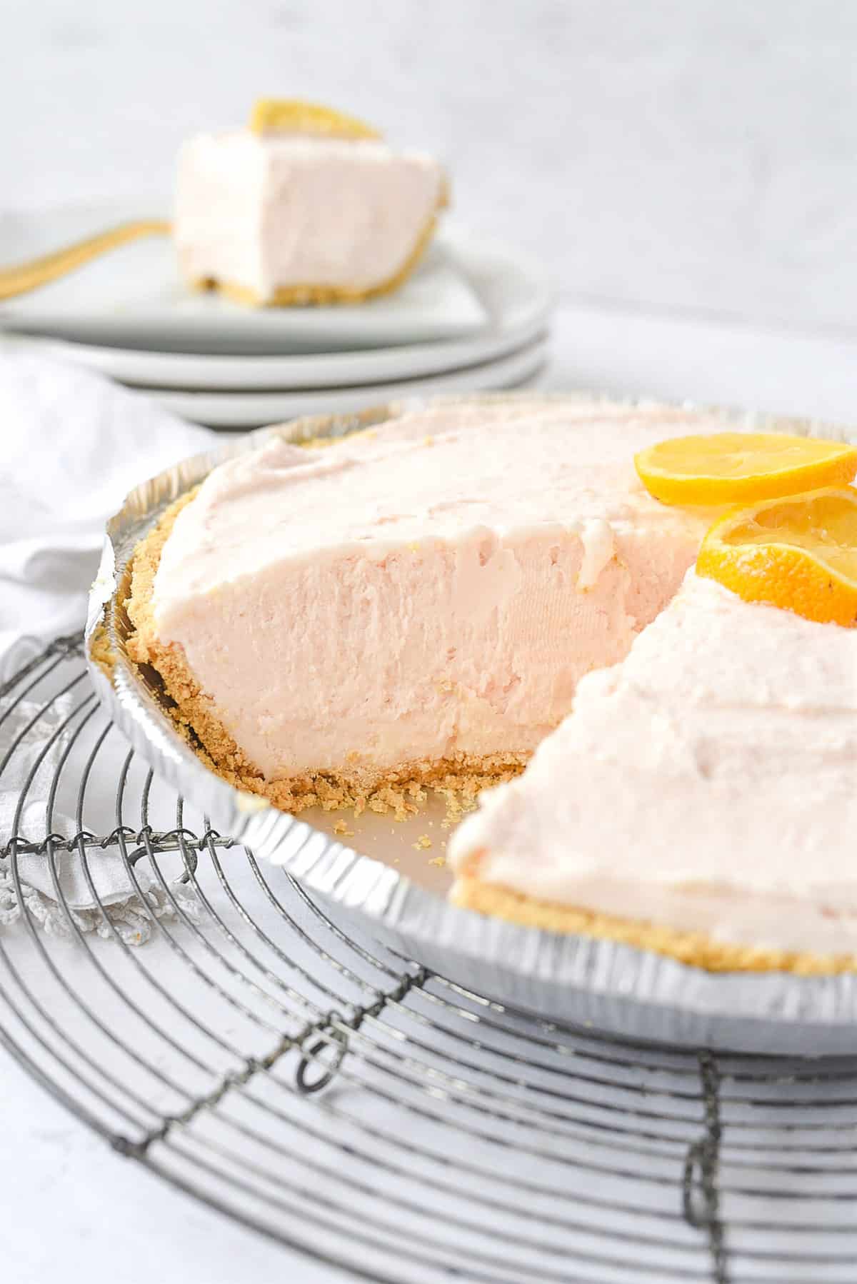 pink lemonade pie on a rack with a piece mkissing