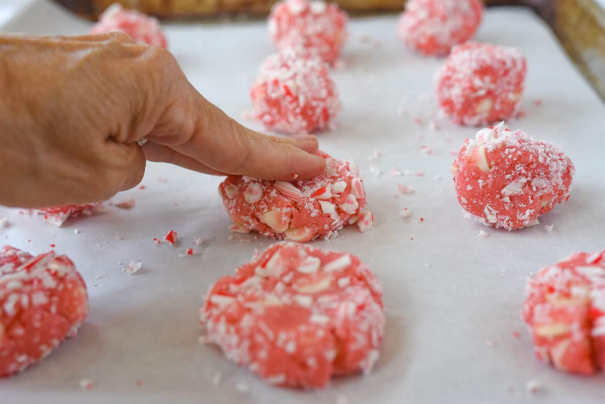 flattening peppermint cookies on baking sheet