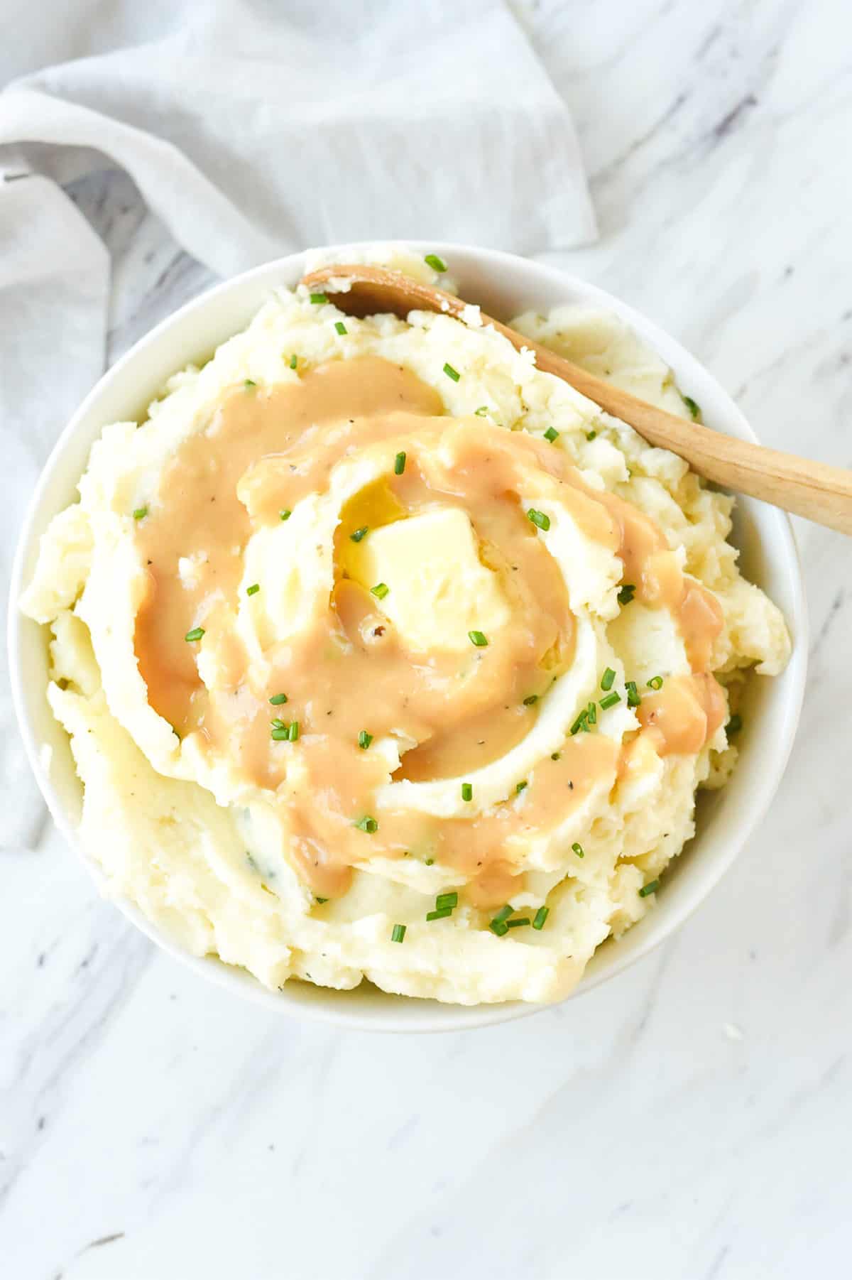 overhead shot of a bowl of mashed potatoes with gravy and butter on top