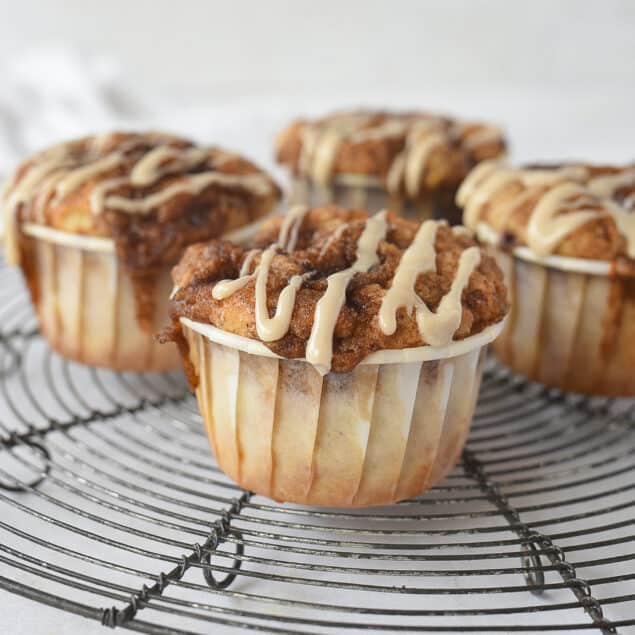four cinnamon roll muffins on a cooling rack