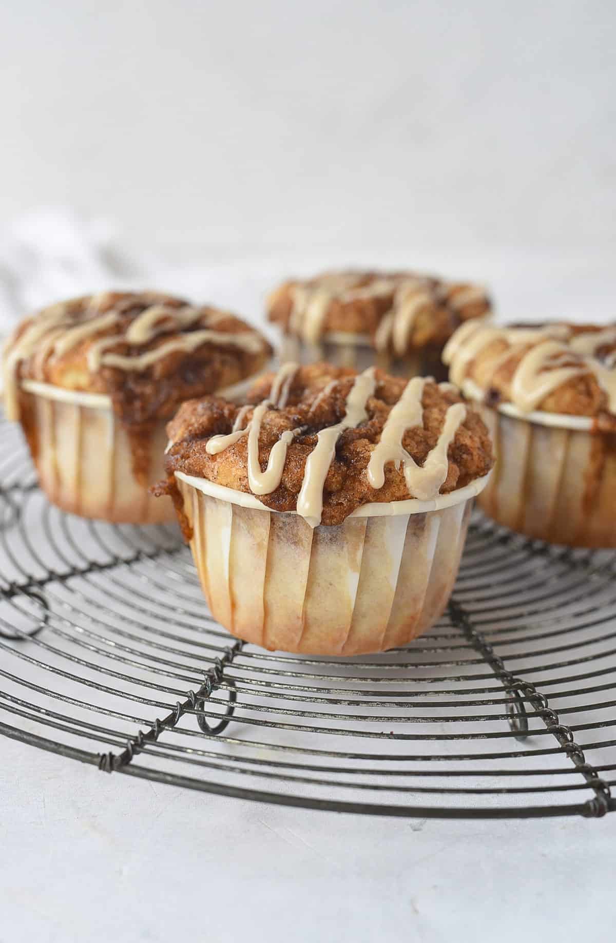 four cinnamon roll muffins on a cooling rack