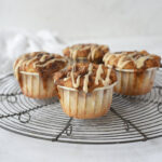 four cinnamon roll muffins on a cooling rack