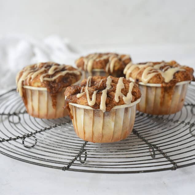 four cinnamon roll muffins on a cooling rack