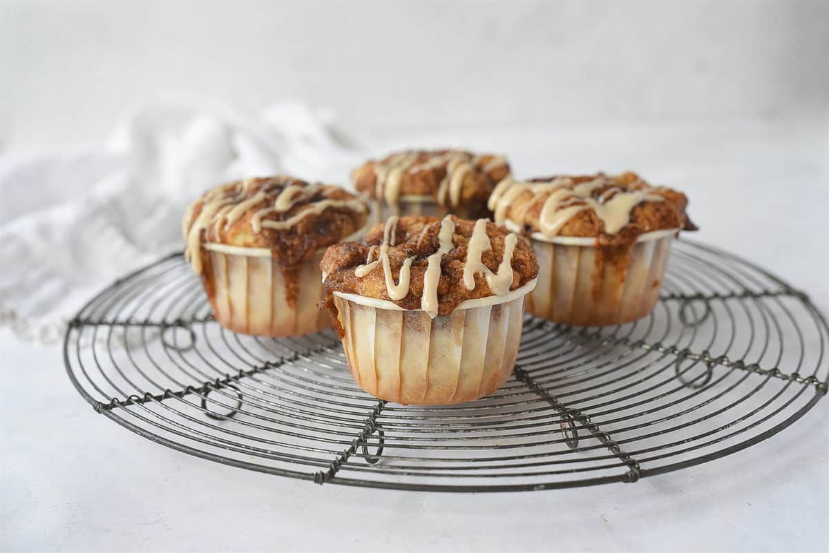four cinnamon roll muffins on a cooling rack