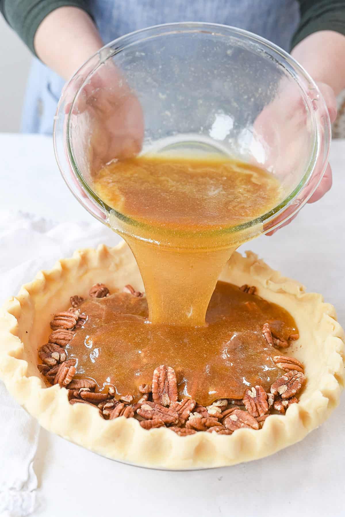 pouring pecan pie filling into pie crust