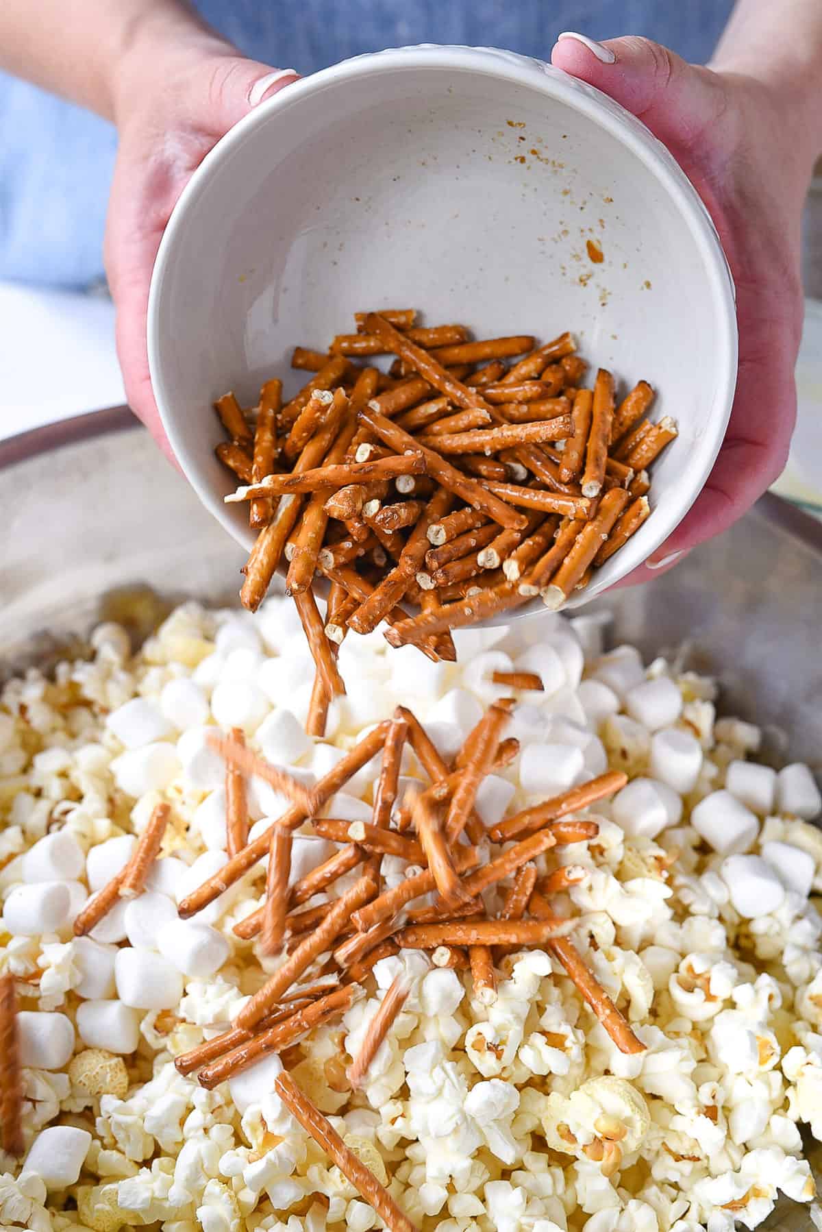 adding pretzels into popcorn