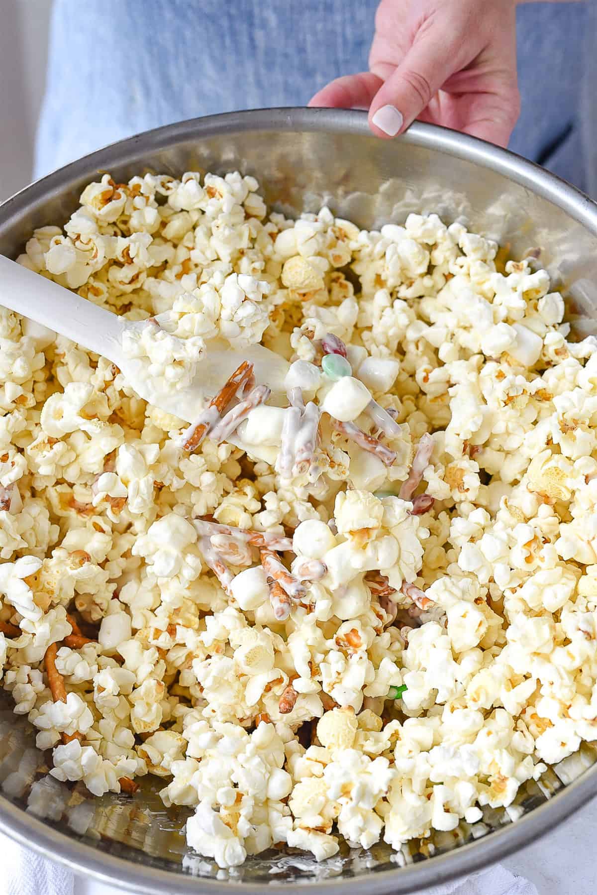 stirring white chocolate popcorn.