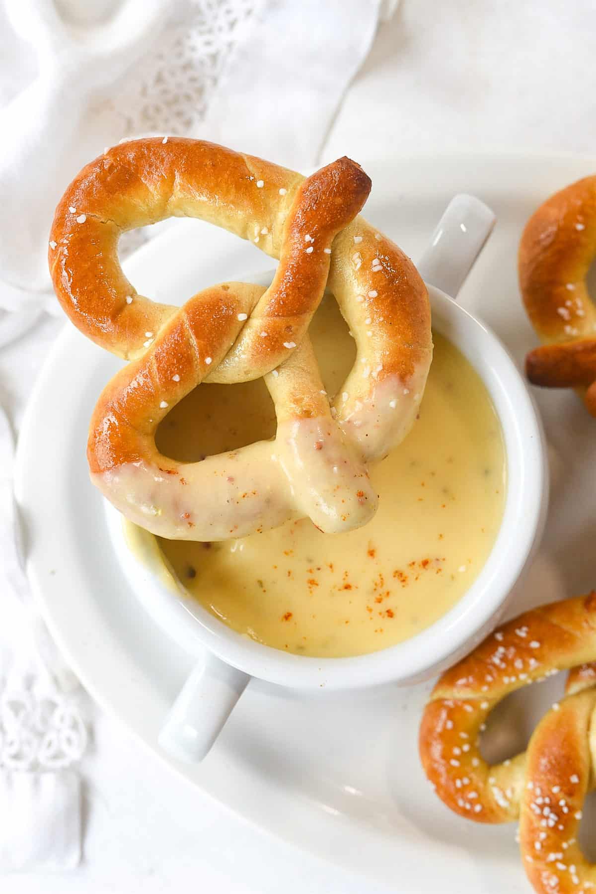 pretzel dipped in cheese sauce on a bowl