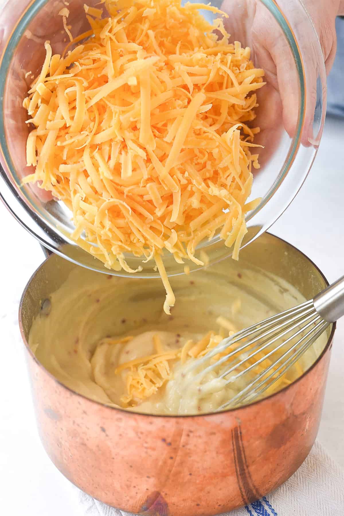 adding cheese to pretzel dipping sauce.