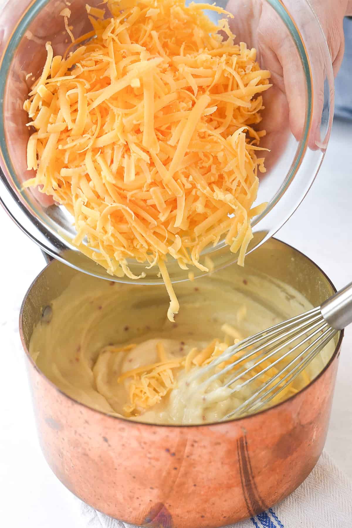 adding cheese to pretzel dipping sauce.