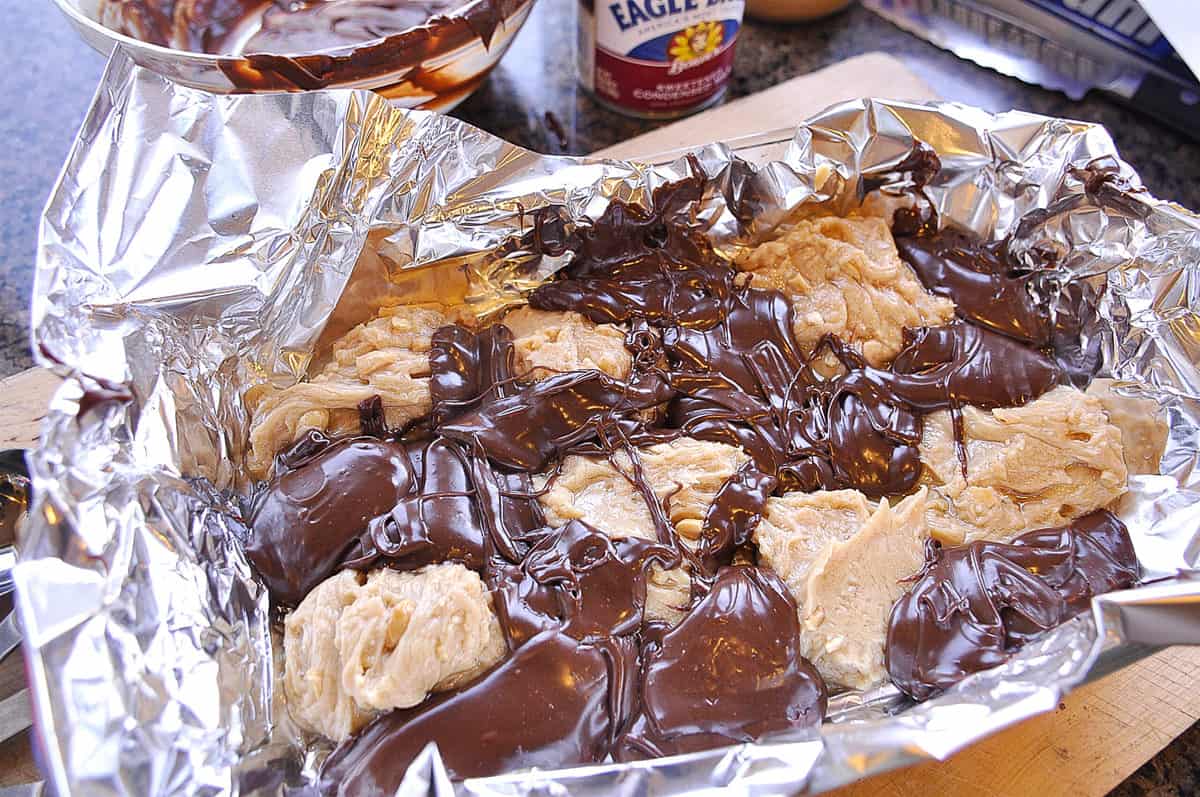 spooning chocolate peanut butter fudge into pan