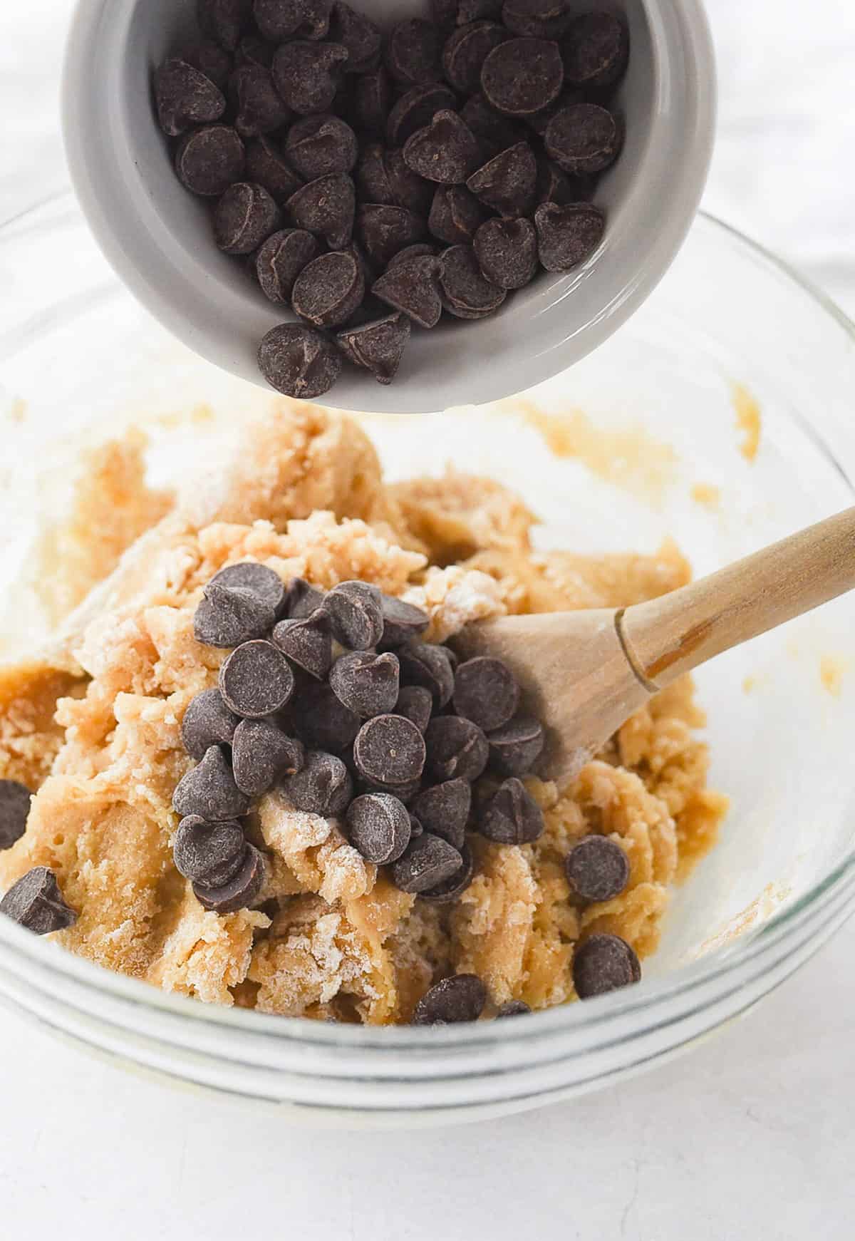 adding chocolate chips to cookie dough