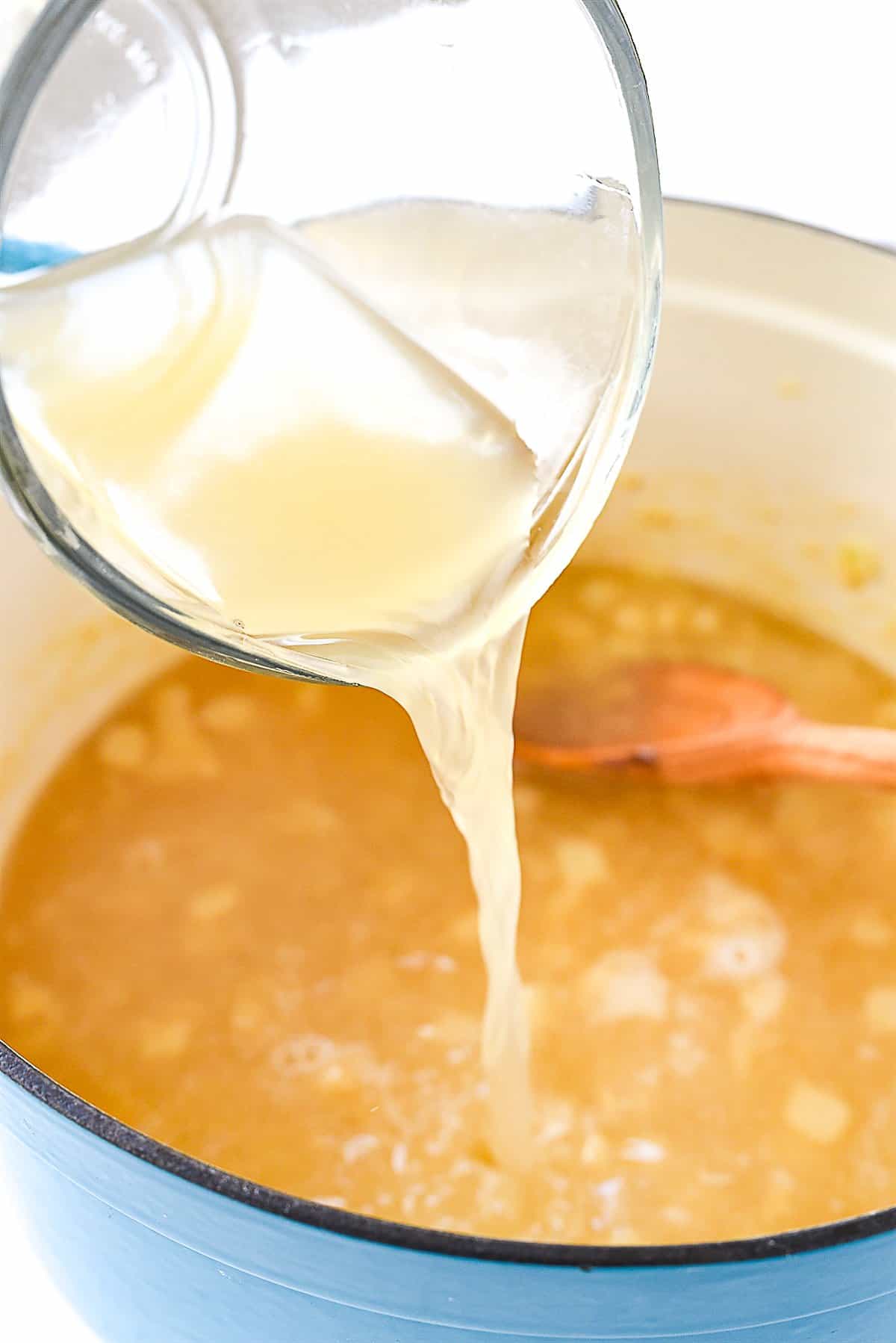 adding chicken broth to soup