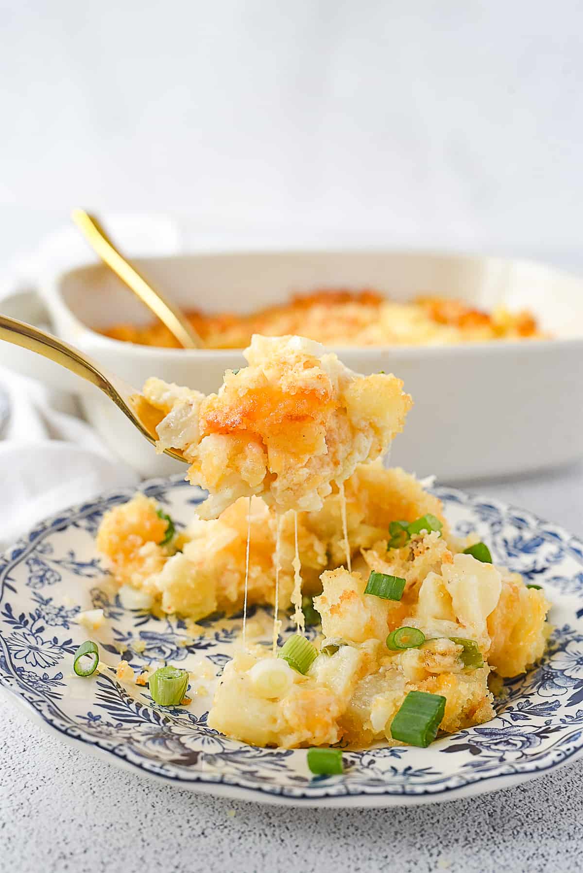 fork full of cheesy potatoes on a plate