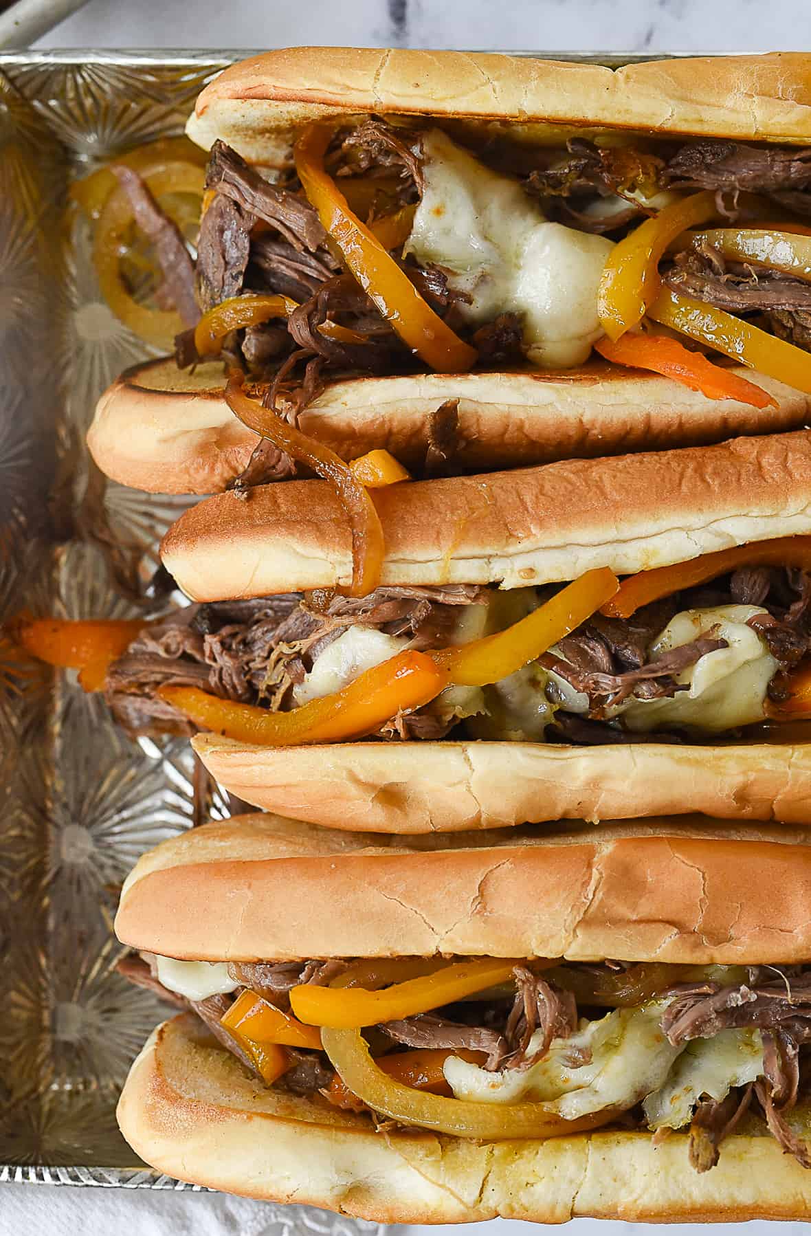 three philly cheese steaks in a pan