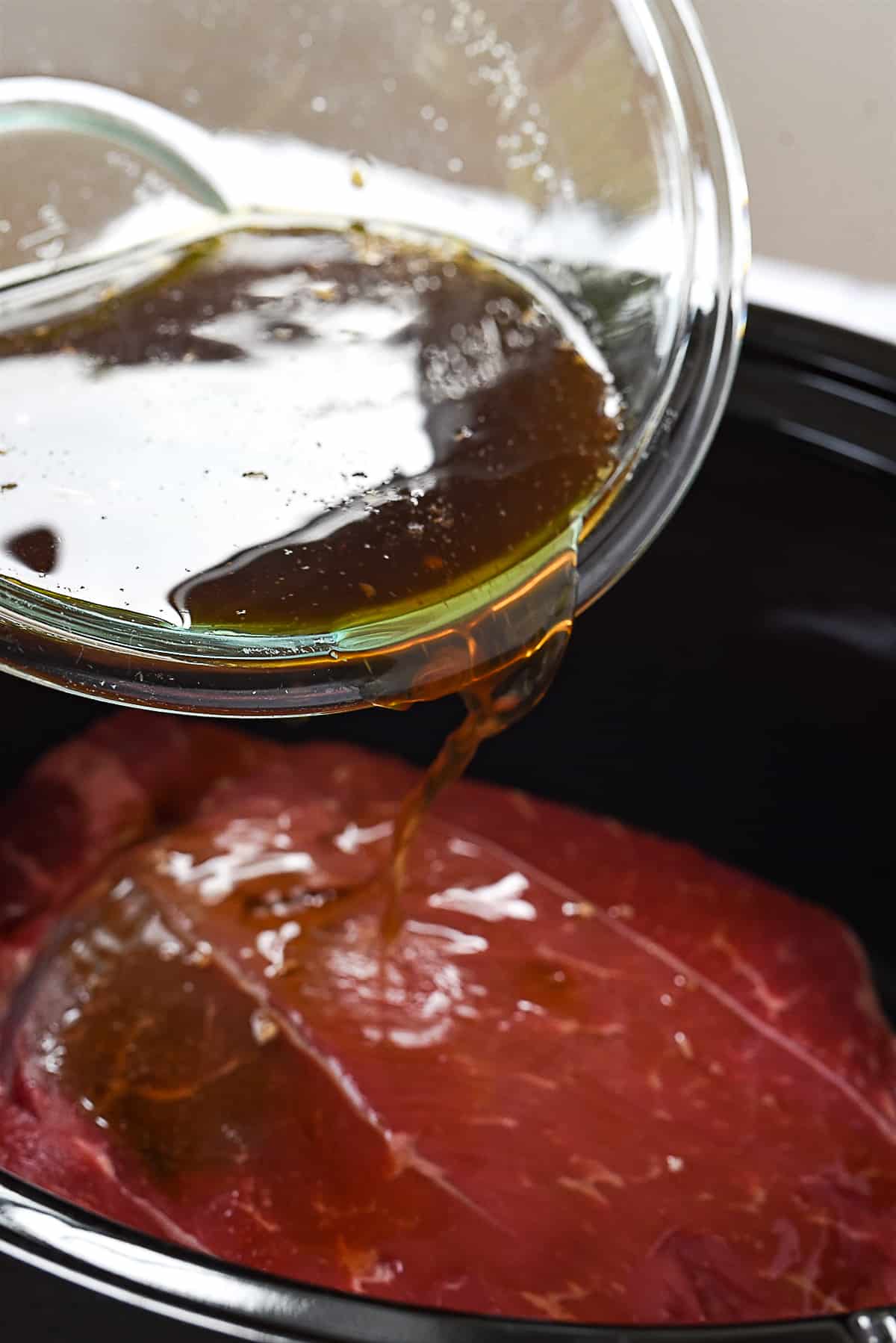 pouring liquid over roast in slow cooker