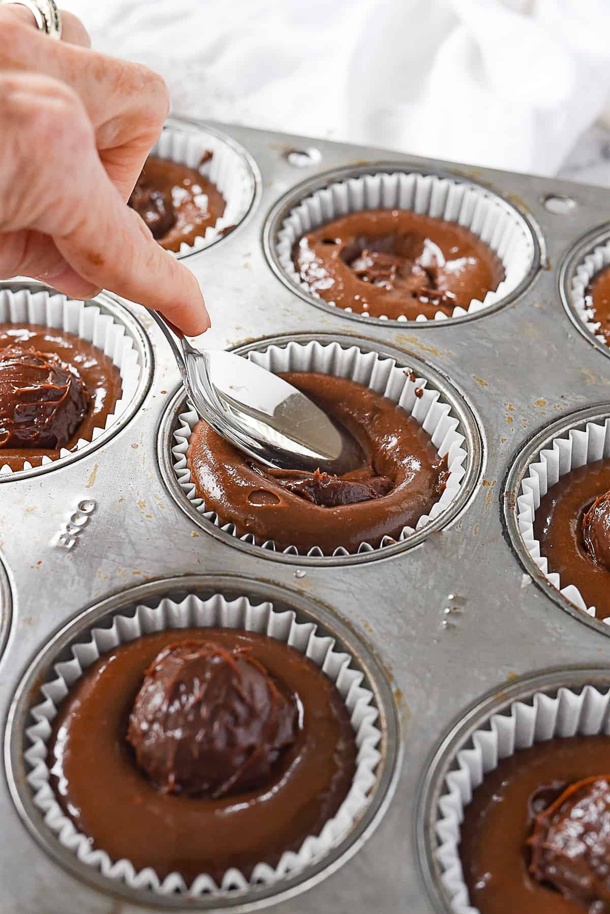 spoon pushing ganache into cupcake