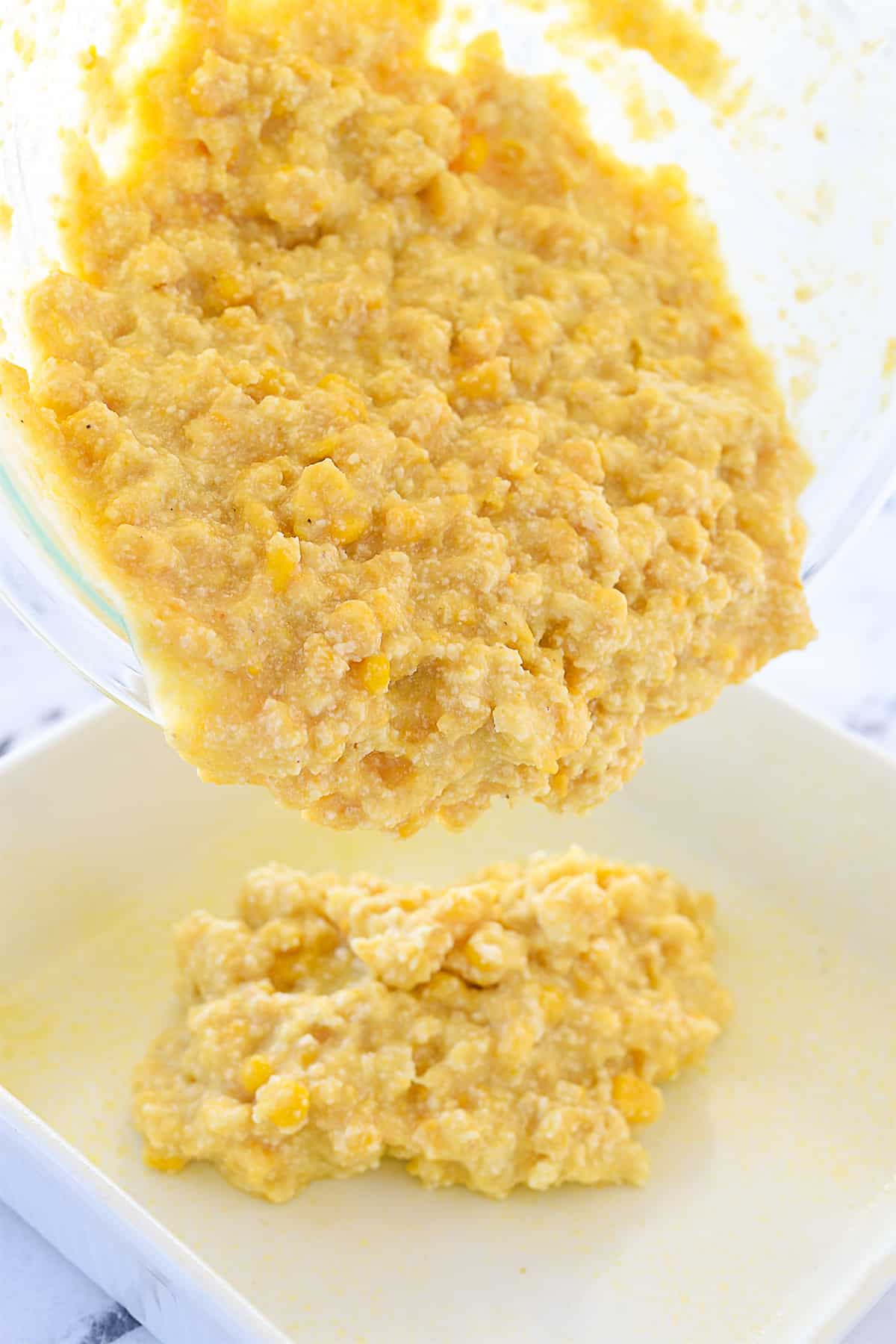 pouring corn casserole into baking dish