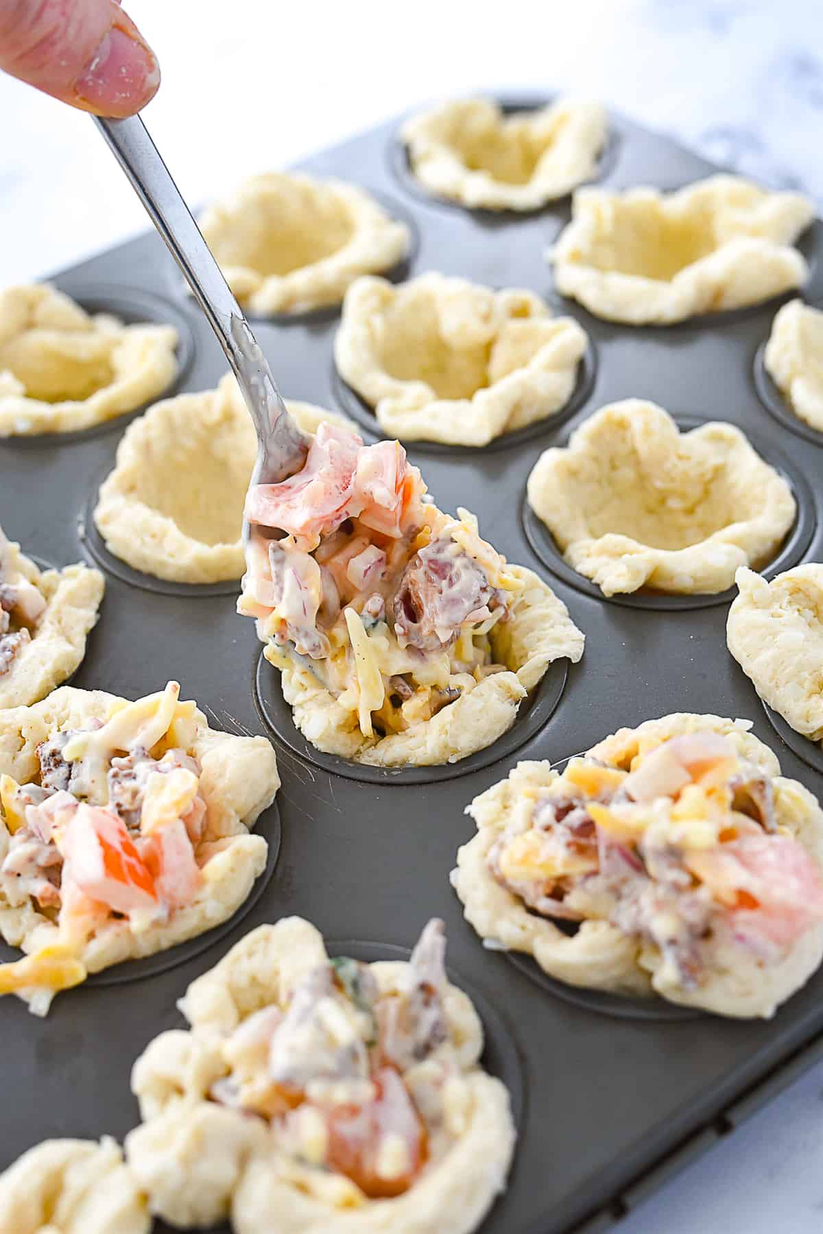 placing cheese mixture into muffin tin