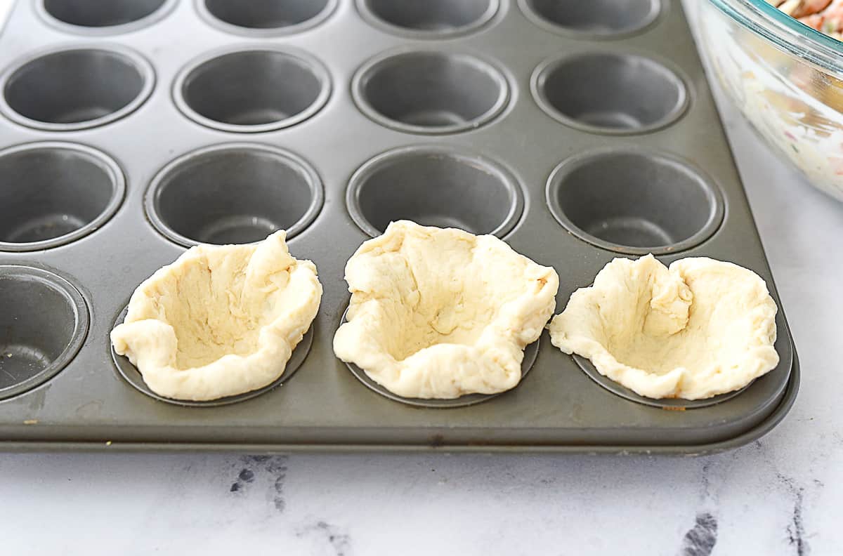 placing biscuit into muffin tin