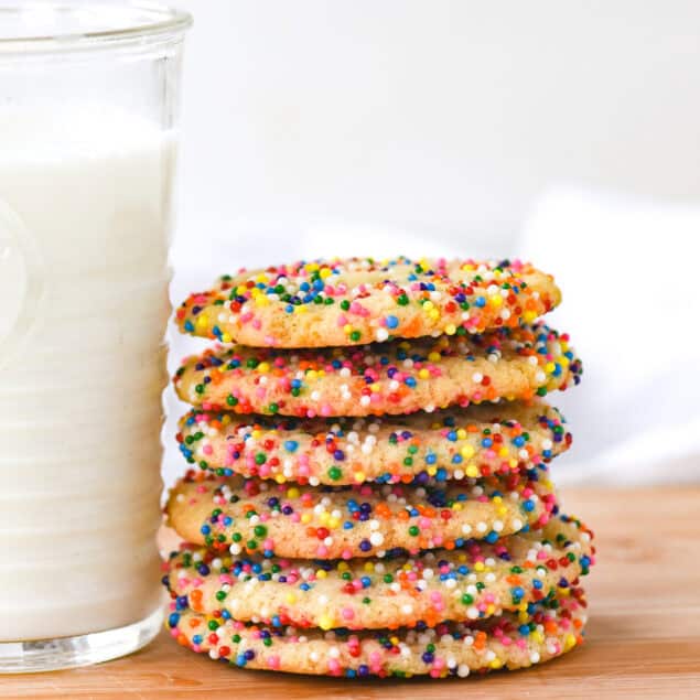 stack of sugar cookies with sprinkles and a glass of milk